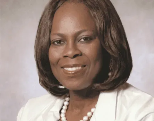 Dr. Olopade headshot. She is smiling, facing forward, wearing a white jacket, with a white pearl necklace.