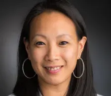 Dr. Kimmie Ng smiling facing forward. She's wearing white coat and hoop earrings.