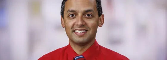 Headshot of Dr. Rahul Banerjee in a clinical setting. He is smiling facing forward