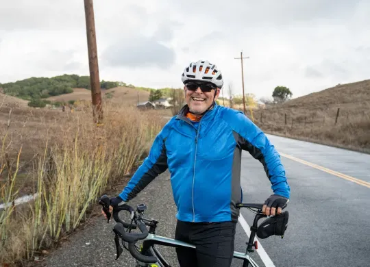 Mark Crafts in an orange shirt, silver helmet, black sunglasses, and electric-blue face-mask