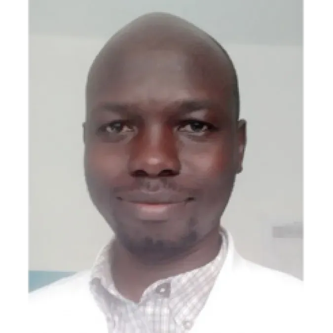 Headshot of Dr. Clement Dove Okello. He is wearing a white coat and is smiling facing forward.