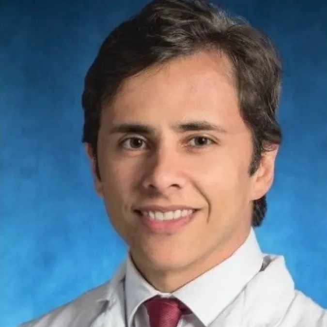 Dr. Pedro Isaacsson Velho in a white coat, smiling facing forward against a blue background.
