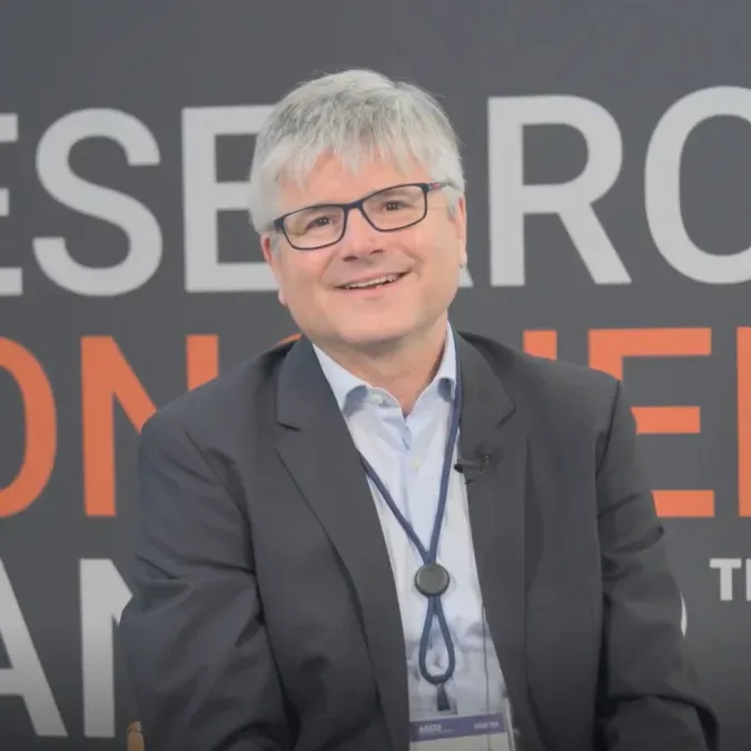Dr. Jaume Mora smiling facing forward against a background that says "Research Conquers Cancer"