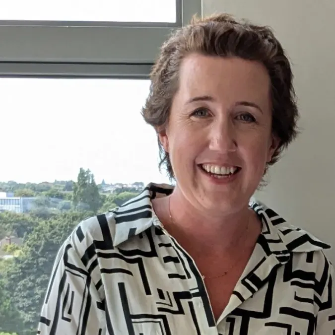Aisling O'Brien smiling facing forward near a window